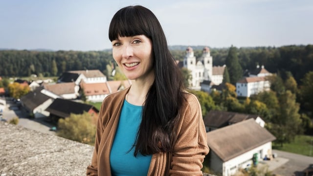 Ein Portrait von Filmemacherin Rebecca Panian, im Hintergrund ist die Zürcher Gemeinde Rheinau zu sehen.