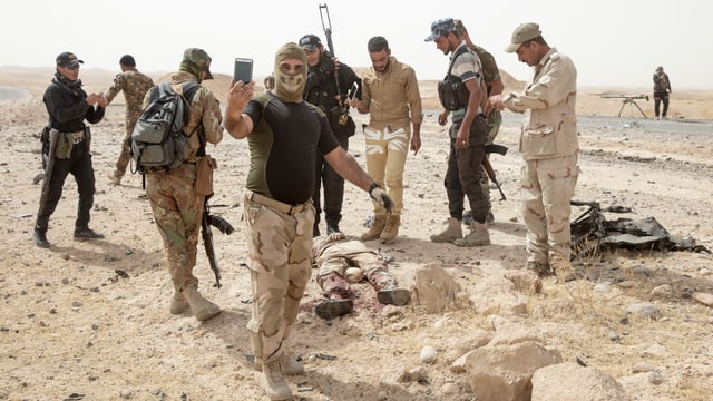 Ein Bild von Soldaten, die um eine Leiche herum stehen. Ein Bild von Soldaten, die um eine Leiche herum stehen.