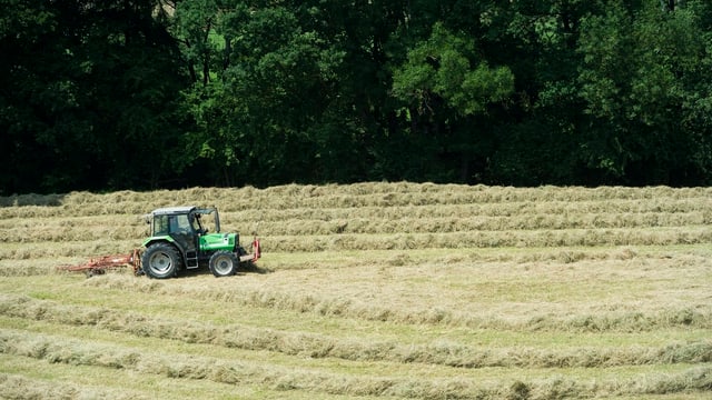Bauer im Traktor beim Heuwenden. Bauer im Traktor beim Heuwenden.