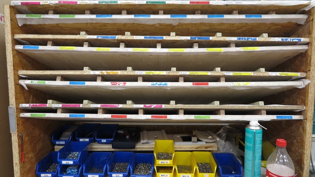 Holzgestell mit verschiedenen Schrauben und andern Metallteilen in Plastikbehältern. Holzgestell mit verschiedenen Schrauben und andern Metallteilen in Plastikbehältern.