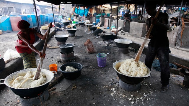 Eine Frau und ein Mann stampfen Maniok-Wurzeln auf einem Markt in Laos, Nigeria. Eine Frau und ein Mann stampfen Maniok-Wurzeln auf einem Markt in Laos, Nigeria.