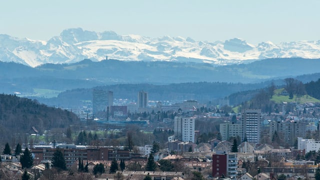 Blick auf eine Stadt, dahinter Hügel und Berge. Blick auf eine Stadt, dahinter Hügel und Berge.
