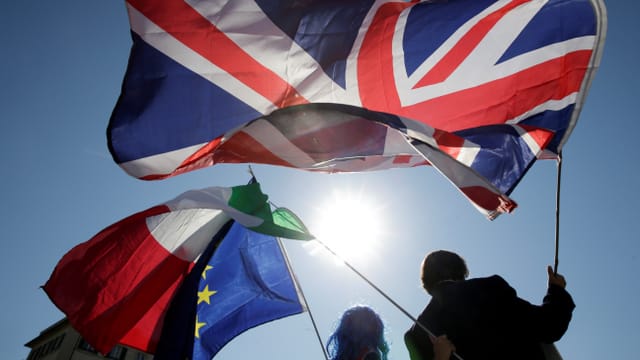 Leute schwingen GB-, Italien- und EU-Flaggen im Gegenlicht der Sonne. Leute schwingen GB-, Italien- und EU-Flaggen im Gegenlicht der Sonne.