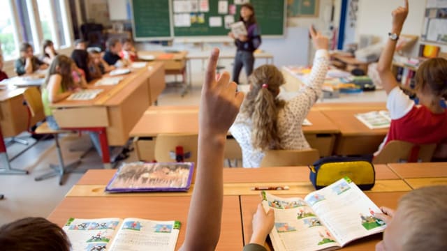 Schüler in einer Schulklasse strecken auf Schüler in einer Schulklasse strecken auf