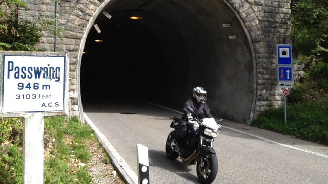 Strasse mit Tunnel und Töff und dem Schild "Passwang, 946 Meter". Strasse mit Tunnel und Töff und dem Schild "Passwang, 946 Meter".