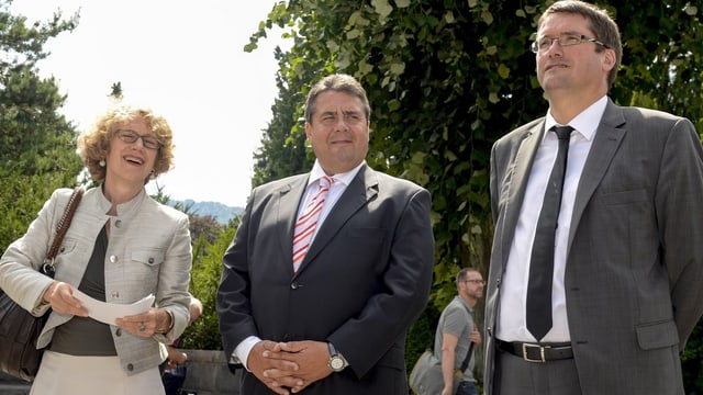 Eine Frau und zwei Männer stehen nebeneinander Eine Frau und zwei Männer stehen nebeneinander