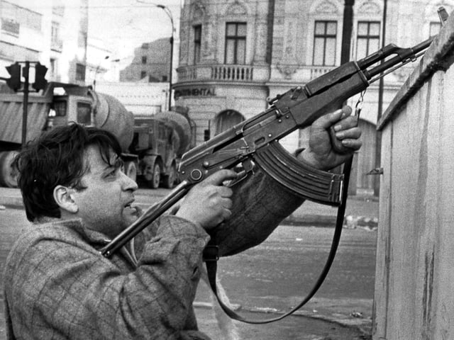 Mann, mit Sturmgewehr aus Deckung schiessend