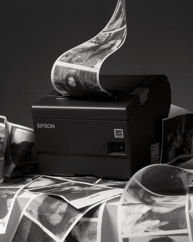 Aus einem kleinen Drucker werden auf einem langen Papierstreifen viele Fotos in Schwarzweiss gedruckt Aus einem kleinen Drucker werden auf einem langen Papierstreifen viele Fotos in Schwarzweiss gedruckt