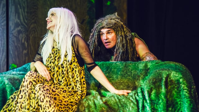 Eine blonde Hippolita sitzt auf einem grünen Sofa, über die Lehne schaut ein Oberon mit Dreadlocks. Eine blonde Hippolita sitzt auf einem grünen Sofa, über die Lehne schaut ein Oberon mit Dreadlocks.