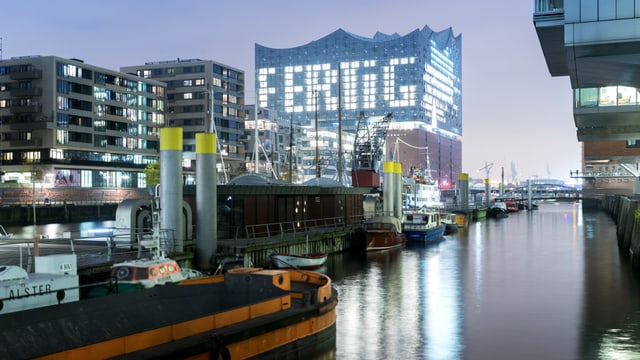 Die fertige Elbphilharmonie, hinter der Glasfassade leuchtet das Wort «fertig». Die fertige Elbphilharmonie, hinter der Glasfassade leuchtet das Wort «fertig».