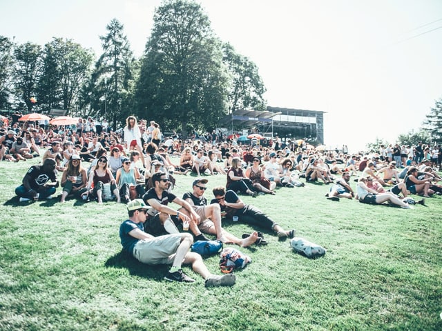 Festival-Besucher sitzen auf dem Boden.