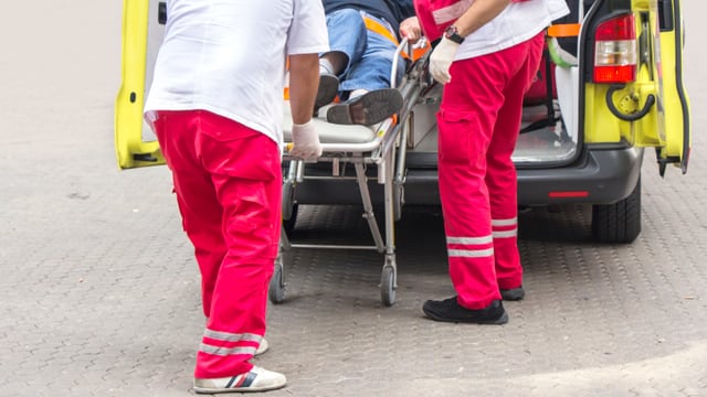 Sanitäter stossen Mann auf Trage in Ambulanz Sanitäter stossen Mann auf Trage in Ambulanz