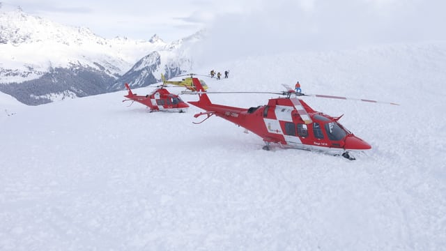 Rote Rega-Helikopter stehen auf dem Lawinenkegel. Rote Rega-Helikopter stehen auf dem Lawinenkegel.