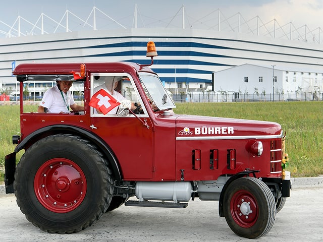 Josef Wyer, Beat Studer und Werner Zimmermann posieren mit einem Traktor (Baujahr: 1964) vor dem Stadion in Kaliningrad. Josef Wyer, Beat Studer und Werner Zimmermann posieren mit einem Traktor (Baujahr: 1964) vor dem Stadion in Kaliningrad.