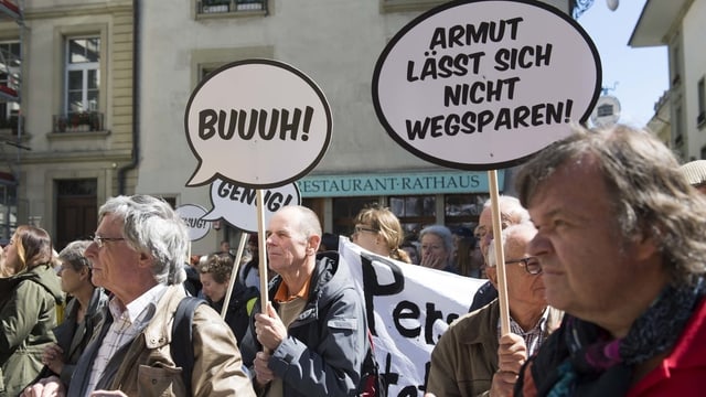 Demonstranten mit Plakaten. Dort steht «Buuuh» und «Armut lässt sich nicht wegsparen» Demonstranten mit Plakaten. Dort steht «Buuuh» und «Armut lässt sich nicht wegsparen»
