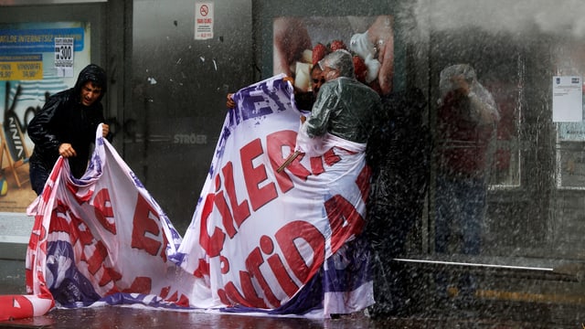 Nasse Demonstraten mit einem Tramsparent vor einem Schaufenster in Ankara.