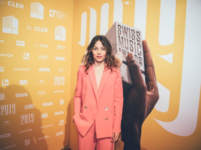Anna Rossinellis Outfit kommt vor der gelben Wand nochmal deutlicher heraus.