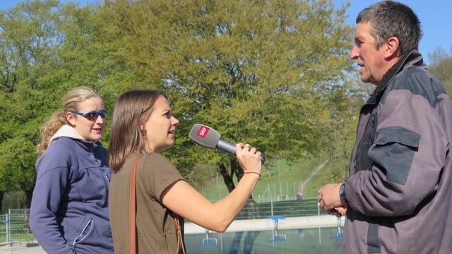 Mann mit Mikrofon vor dem Gesicht. Zwei Frauen daneben. Mann mit Mikrofon vor dem Gesicht. Zwei Frauen daneben.