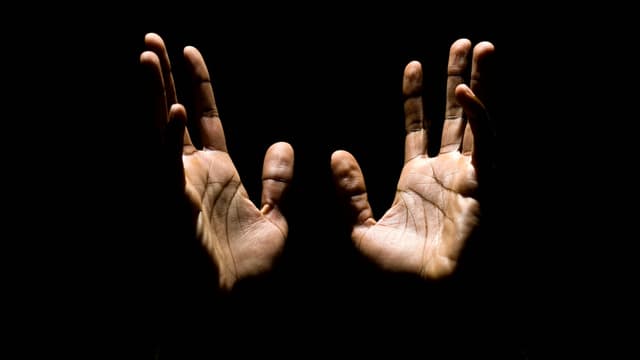 Zwei männliche Hände strecken vor scharzem Hintergrund gegen oben. Zwei männliche Hände strecken vor scharzem Hintergrund gegen oben.