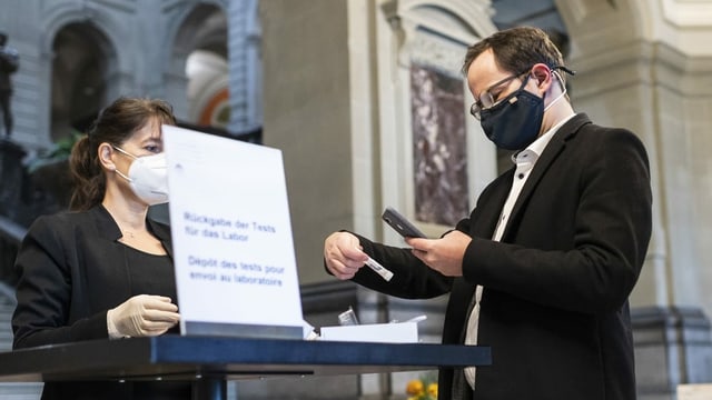 Nationalrat der Grünen Balthasar Glättli registriert seinen Covid-19 Test, bevor er ihn der Mitarbeiterin der Parlamentsdienste, Agathe Casutt gibt. Nationalrat der Grünen Balthasar Glättli registriert seinen Covid-19 Test, bevor er ihn der Mitarbeiterin der Parlamentsdienste, Agathe Casutt gibt.