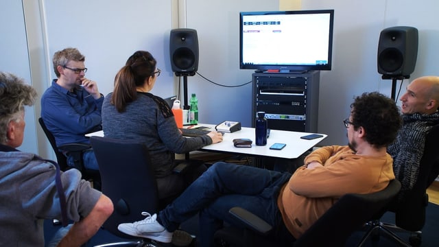 Mehrere Menschen hören sich gemeinsam im Büro einen Song an. Mehrere Menschen hören sich gemeinsam im Büro einen Song an.