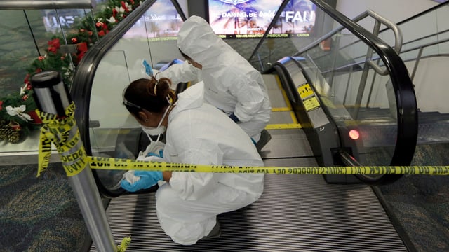 Zwei weiss gekleidete Menschen putzen die Rolltreppe am Flughafen. Absperrband. Zwei weiss gekleidete Menschen putzen die Rolltreppe am Flughafen. Absperrband.