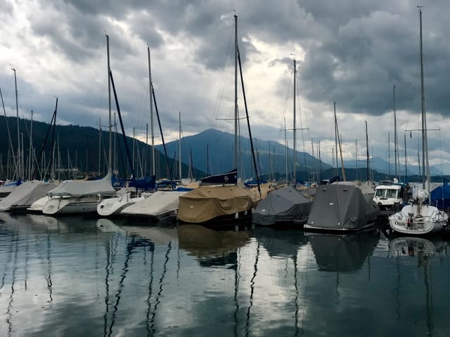 Schiffe liegen am Steeg fest, der Himmel über dem See ist mit grauen Wolken überzogen.