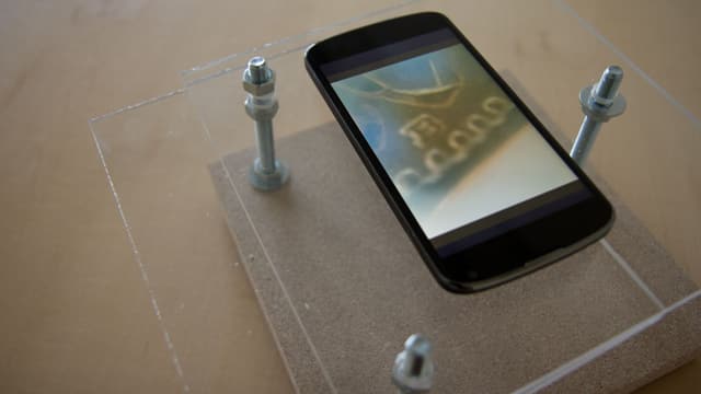 Handy auf Plexiglasplatte von einem Gestell gehalten. Handy auf Plexiglasplatte von einem Gestell gehalten.