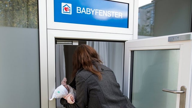 Eine Frau legt eine Pupe ins Babyfenster. Eine Frau legt eine Pupe ins Babyfenster.