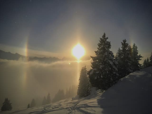 Sonne über verschneitem Berg.