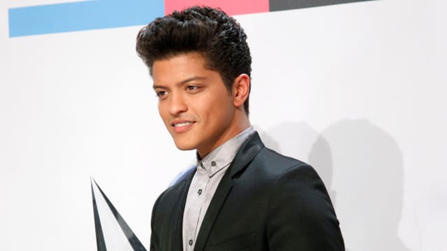 Bruno Mars im schwarzen Anzug vor einer Fotowand Bruno Mars im schwarzen Anzug vor einer Fotowand