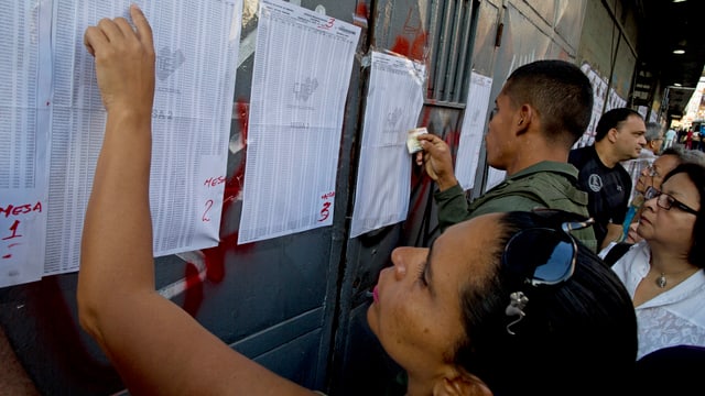 Vor einem Wahllokal in Caracas suchen Bewohner nach ihren Namen auf den Wahllisten. Vor einem Wahllokal in Caracas suchen Bewohner nach ihren Namen auf den Wahllisten.