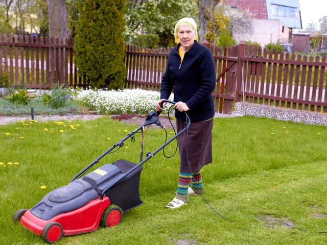 Seniorin mit Wollsocken, Birkenstock und Kopfbedeckung am Rasenmähen Seniorin mit Wollsocken, Birkenstock und Kopfbedeckung am Rasenmähen