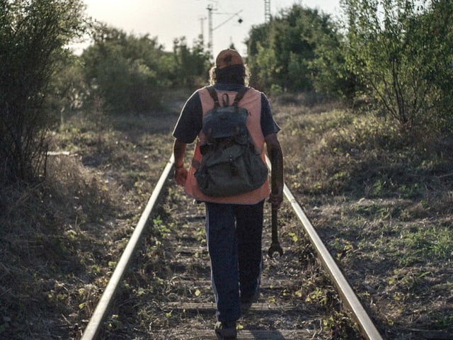 Ein Mann läuft auf einem Bahngleis entlang. Ein Mann läuft auf einem Bahngleis entlang.