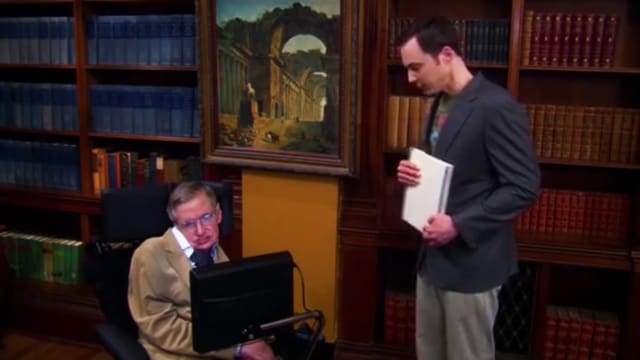 Stephen Hawking schaut auf einen Computer. Neben ihm steht ein Student. Stephen Hawking schaut auf einen Computer. Neben ihm steht ein Student.