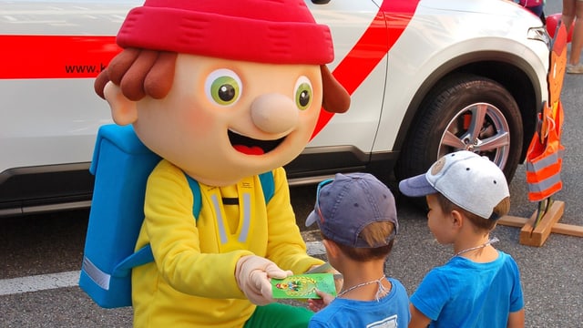 Maskottchen Simi Sicherli verteilt Malbüechli an kleine Kinder Maskottchen Simi Sicherli verteilt Malbüechli an kleine Kinder
