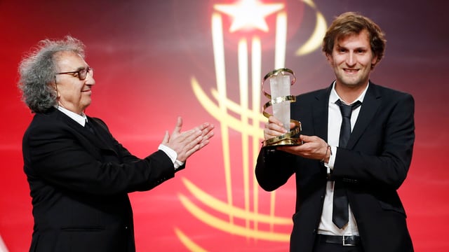 Regisseur Simon Jaquemet 2014 mit Pokal auf der Bühne des Filmfestivals von Marrakesch. Regisseur Simon Jaquemet 2014 mit Pokal auf der Bühne des Filmfestivals von Marrakesch.