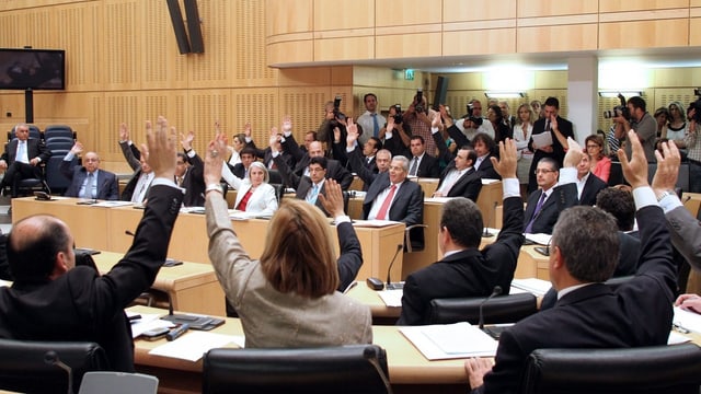 Das zyprische Parlament stimmt ab; die Abgeordneten halten ihre Hände auf. Das zyprische Parlament stimmt ab; die Abgeordneten halten ihre Hände auf.