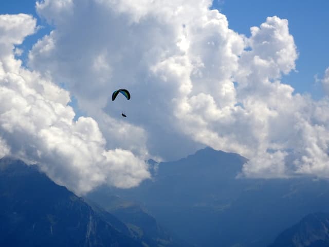 Quellwolken in den Bergen mit einem Gleitschirm im Vordergrund. Quellwolken in den Bergen mit einem Gleitschirm im Vordergrund.