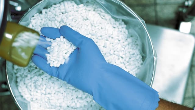 Handschuh sammelt Tabletten aus Maschine