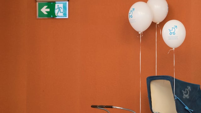 Ein Kinderwagen mit Ballons steht vor einem Exit-Schild. Ein Kinderwagen mit Ballons steht vor einem Exit-Schild.