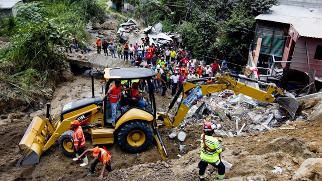 Bulldozer an einem Hügel mit zerstörten Gebäuden Bulldozer an einem Hügel mit zerstörten Gebäuden