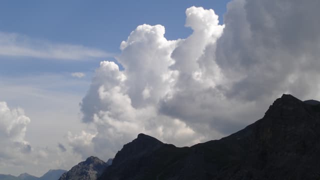 Bergkamm vor blauem Himmel. Über der Krete wachsen Wolkentürme in die Luft. Bergkamm vor blauem Himmel. Über der Krete wachsen Wolkentürme in die Luft.