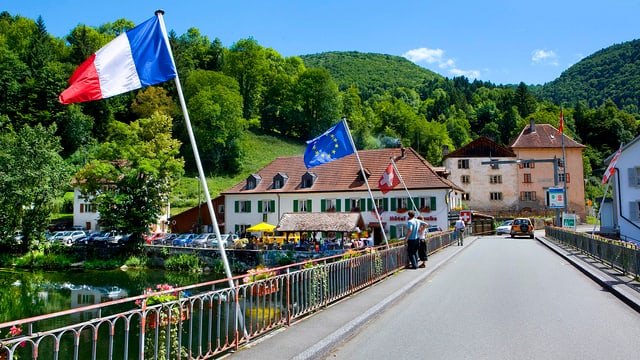 Frankreich-, EU- und Schweizerflagge, Gebäude, Wald im Hintergrund Frankreich-, EU- und Schweizerflagge, Gebäude, Wald im Hintergrund