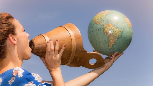Frau jodelt und hält einen Globus in der Hand Frau jodelt und hält einen Globus in der Hand