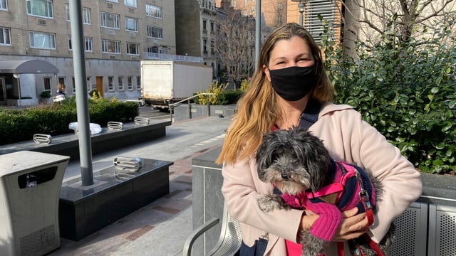Eine Frau mit kleinem Hund auf den Armen lächelt in die Kamera. Eine Frau mit kleinem Hund auf den Armen lächelt in die Kamera.