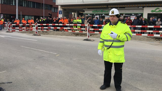 Mann in gelber Schutzweste vor Zuschauern Mann in gelber Schutzweste vor Zuschauern