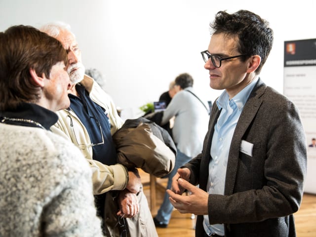 Drei Menschen sprechen in einem Raum miteinander
