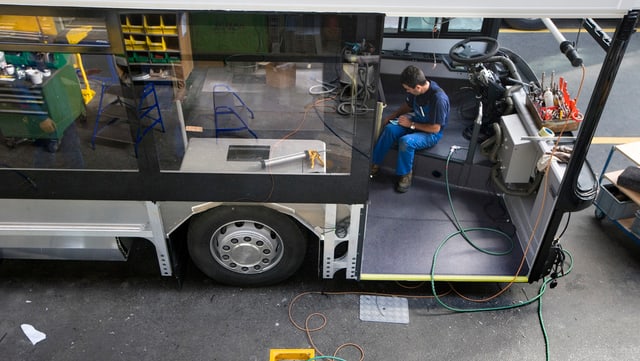 Arbeiter arbeitet an einem halbfertigen Bus Arbeiter arbeitet an einem halbfertigen Bus