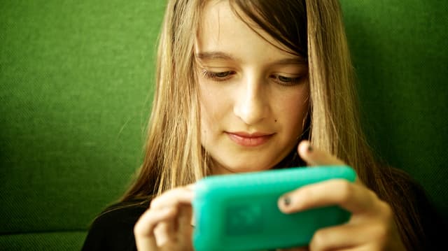 Ein Mädchen schaut in einen iPod Touch. Ein Mädchen schaut in einen iPod Touch.